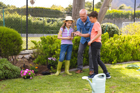 Caucasian children and grandfather spending time together in the garden, planting. Family time...