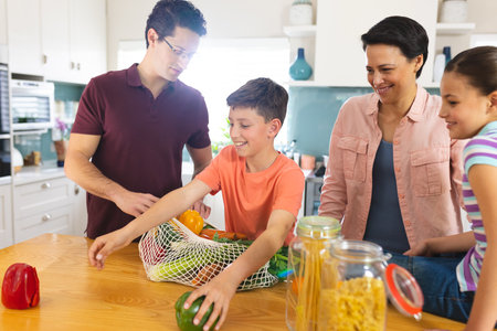 Caucasian family unpacking shopping bag together in the modern kitchen. Spending family time together at home.の写真素材