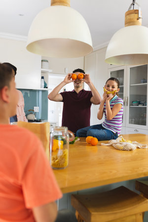 Vertical picture of caucasian children unpacking shopping bag together in the modern kitchen. Spending family time together at home.の写真素材
