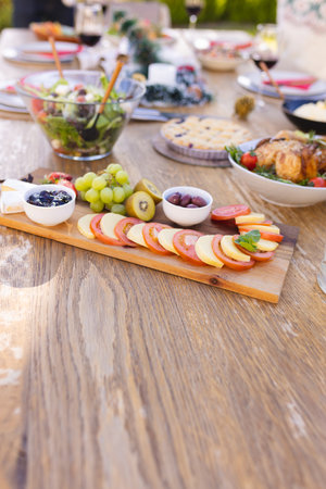Vertical picture of a wooden table prepared for a meal in the sunny garden. Spending time together outside.の写真素材