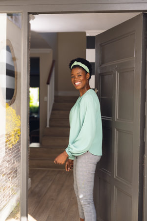 Vertical picture of happy african american women welcoming some body outside the house. Spending...