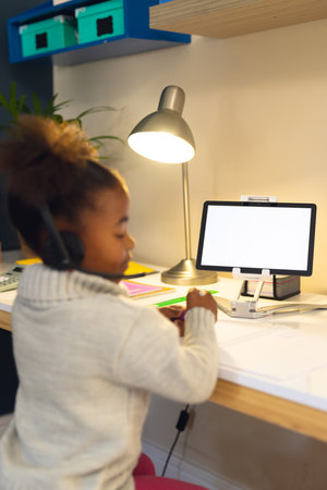 Vertical picture of happy african american girl learning, using tablet at home. Home education,...