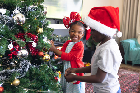 African american siblings spending time together and decorating christmas tree. Christmas, family time and celebration concept.の写真素材
