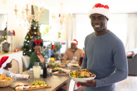 Happy african american family spending time together having christmas meal. Christmas, family time and celebration concept.の写真素材