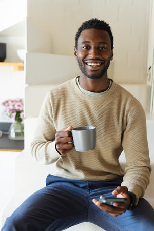 Portrait of happy african american man looking at camera and smiling. Spending quality time at home alone.の写真素材