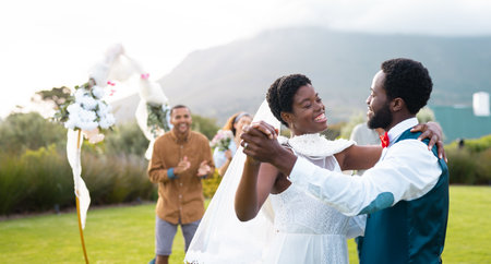 Happy african american couple holding hands and dancing during wedding. Wedding day, friendship, inclusivity and lifestyle concept.の写真素材