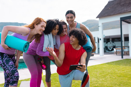 Diverse friends using smartphone and holding yoga mats in garden. Health, celebration, friendship, inclusivity and lifestyle concept.の写真素材