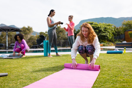 Diverse friends talking and rolling yoga mats in garden. Health, celebration, friendship, inclusivity and lifestyle concept.の写真素材