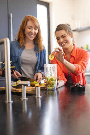 Happy diverse friends making healthy drink together in kitchen. Party, celebration, friendship, inclusivity and lifestyle concept.の写真素材
