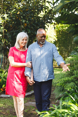 Happy senior diverse couple walking in garden. Spending quality time at home and retirement concept.の写真素材