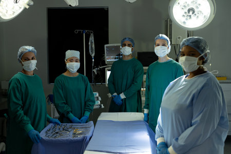 Diverse team of surgeons and techs ready for operation, standing around operating table in theatre....