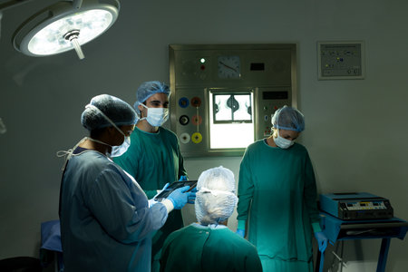 Diverse group of surgeons in discussion, using tablet in operating theatre before operation....