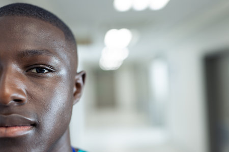 Portrait of half the face of african american male healthcare worker in corridor, copy space. Hospital, medical and healthcare services.の写真素材