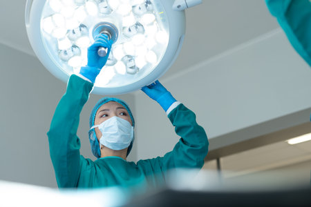 Asian female surgeon adjusting lights in operating theatre for operation, with copy space. Hospital, medical and healthcare services.の写真素材