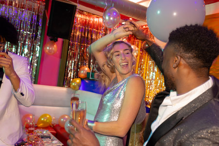 Happy diverse couple dancing and drinking champagne at a nightclub. Fun, drinking, going out,...