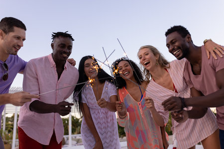 Happy diverse friends having party by swimming pool, holding sparklers. Spending quality time,...