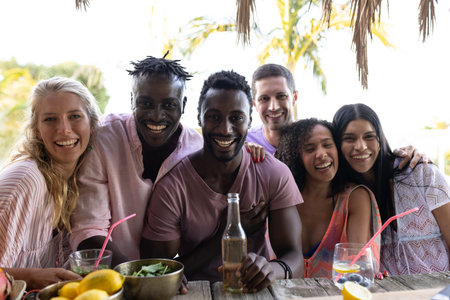 Portrait of happy diverse friends embracing and smiling at beach, with copy space. Spending quality time, lifestyle, friendship, summertime and vacation concept.の写真素材