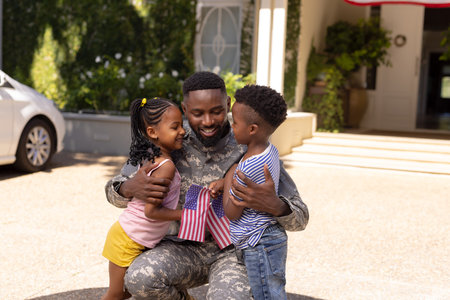 African american army soldier father embracing cute children outside house. Unaltered, family, together, childhood, pride, military, flag of america, patriotism and homecoming concept.の写真素材