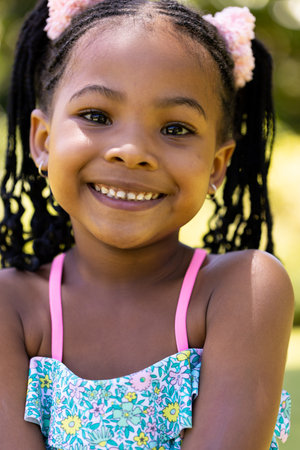 Closeup portrait of smiling african american cute girl with dreadlocks looking at camera. Unaltered,...