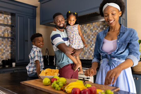 African american smiling husband and children looking at woman chopping fruits on kitchen counter. Copy space, unaltered, family, togetherness, childhood, fresh, healthy, lifestyle and home concept.の写真素材