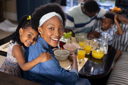 High angle portrait of cheerful african american mother and daughter sitting at dining table at home. Unaltered, family, togetherness, childhood, food, fresh, happy and lifestyle concept.の写真素材
