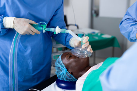 Midsection of surgeon giving african american male patient anesthetic mask in operating theatre. Surgery, hospital, medical and healthcare services.の写真素材