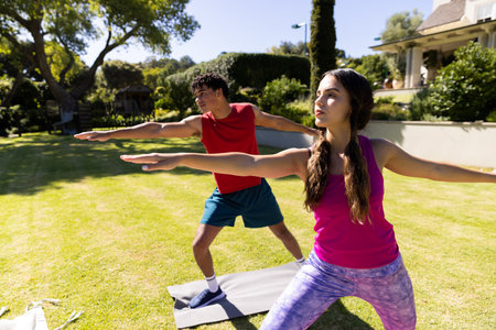 Happy diverse fit couple practicing yoga standing and stretching in sunny garden. Summer, healthy...