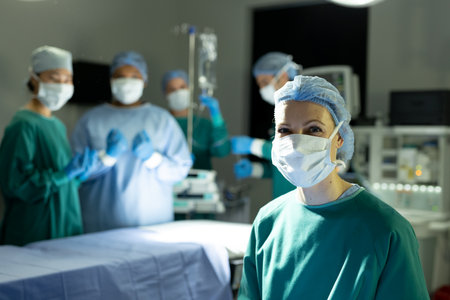 Portrait of smiling caucasian female surgeon in theatre for operation with colleagues, copy space....
