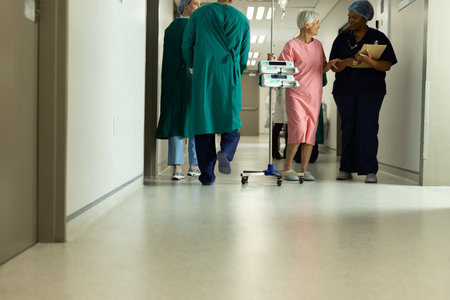 Diverse female doctor and caucasian senior female patient with iv pole talking in hospital. Hospital, medical and healthcare services, copy space.の写真素材