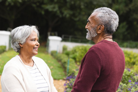 Happy senior biracial couple holding hands, smiling in garden at home. Senior lifestyle, retirement, nature and domestic life, unaltered.の写真素材