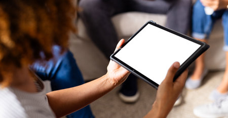 Diverse group of friends using tablet with copy space and talking in group therapy session. Therapy, mental health, friendship, communication and support, unaltered.の写真素材