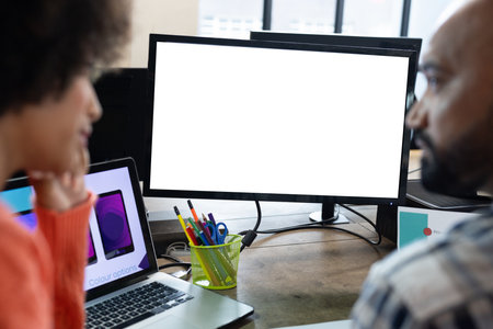 Rear view of diverse male and female designers discussing at computer with copy space in office. Creative business, design, technology, teamwork and casual office.の写真素材