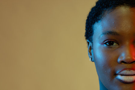 African american woman with short hair and white lipstick in blue and red light, copy space. Femininity, face, facial expressions, body, skin, makeup, fashion and beauty, unaltered.の写真素材