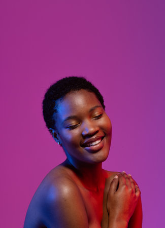 African american woman smiling with eyes closed in blue and red light with purple copy space. Femininity, face, facial expressions, body, skin, makeup, fashion and beauty, unaltered.の写真素材