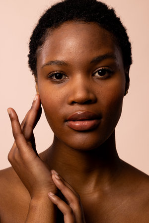 Vertical of african american woman with short hair touching hands and face. Femininity, face, facial expressions, body, skin, makeup, fashion and beauty, unaltered.の写真素材