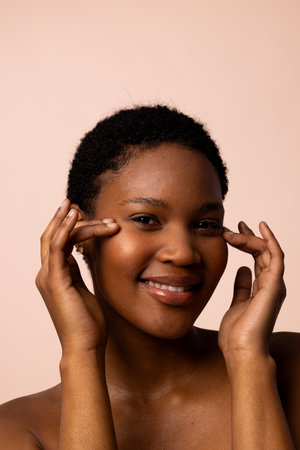 African american woman with short hair looking away smiling and touching temples. Femininity, face, facial expressions, body, skin, makeup, fashion and beauty, unaltered.の写真素材