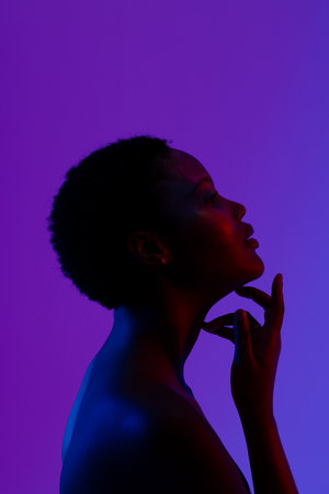 African american woman with short hair touching chin on purple background, copy space. Femininity, face, facial expressions, body, skin, makeup, fashion and beauty, unaltered.の写真素材