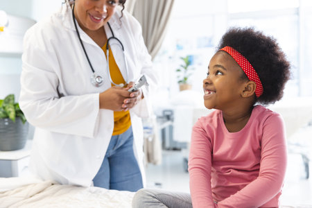 Happy african american female doctor talking to girl patient at hospital. Hospital, medicine and healthcare, unaltered.