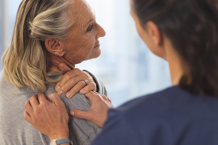 Caucasian female physiotherapist and senior woman massaging back at hospital. Hospital, physiotherapy, work, medicine and healthcare, unaltered.の写真素材