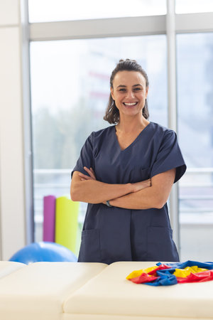 Portrait of happy female caucasian physiotherapist wearing scrubs at hospital. Hospital,...