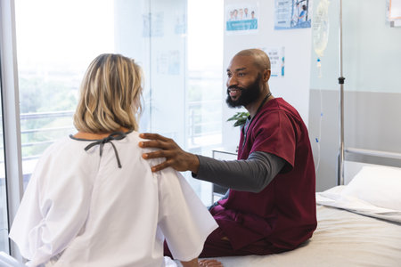African american male doctor talking to senior female caucasian patient at hospital. Hospital, work, medicine and healthcare, unaltered.の写真素材