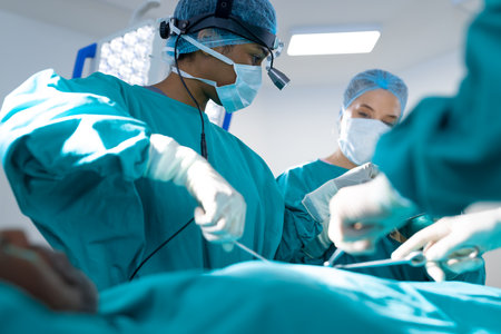 Diverse surgeons wearing surgical gowns operating on patient in operating theatre at hospital....