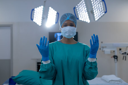Portrait of african american female surgeon wearing surgical gown in operating theatre at hospital. Hospital, surgery, hygiene, medicine, healthcare and work, unaltered.の写真素材