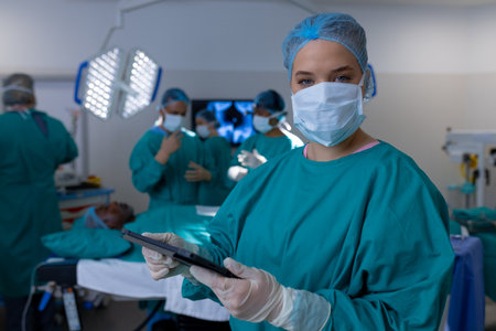 Portrait of caucasian female surgeon wearing surgical gown in operating theatre at hospital. Hospital, surgery, hygiene, medicine, healthcare and work, unaltered.の写真素材