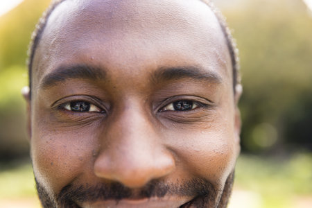 Portrait close up of smiling african american man in sunny garden. Wellbeing, summer, nature and...