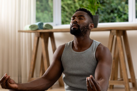 Focused african american man practicing yoga meditation at home. Lifestyle, wellbeing, exercise, fitness and domestic life, unaltered.の写真素材