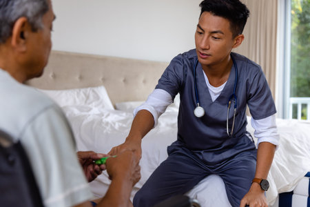 Diverse male doctor discussing medication with senior male patient in wheelchair at home. Medical services, check up, home visit, healthcare, wellbeing and senior lifestyle, unaltered.の写真素材