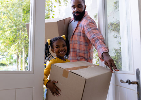African american father and daughter with carboard boxes entering in new home. Unaltered, family, love, togetherness, childhood, door, moving house and relocation concept.の写真素材
