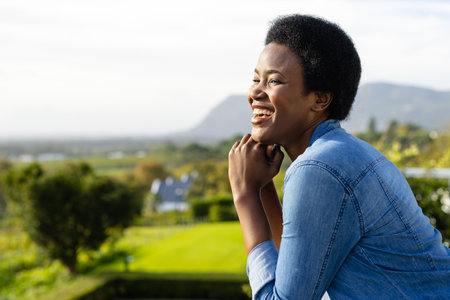Profile of happy african american woman staying on sunny terrace with copy space. Lifestyle, nature and domestic life, unaltered.の写真素材