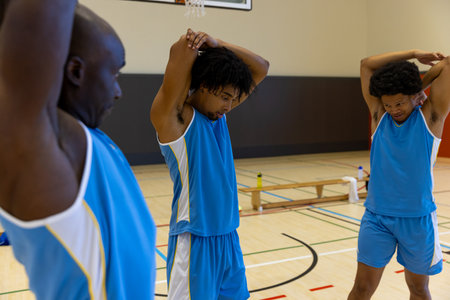 Diverse male basketball players stretching and warming up at gym. Sport, activity, togetherness and lifestyle, unaltered.の写真素材